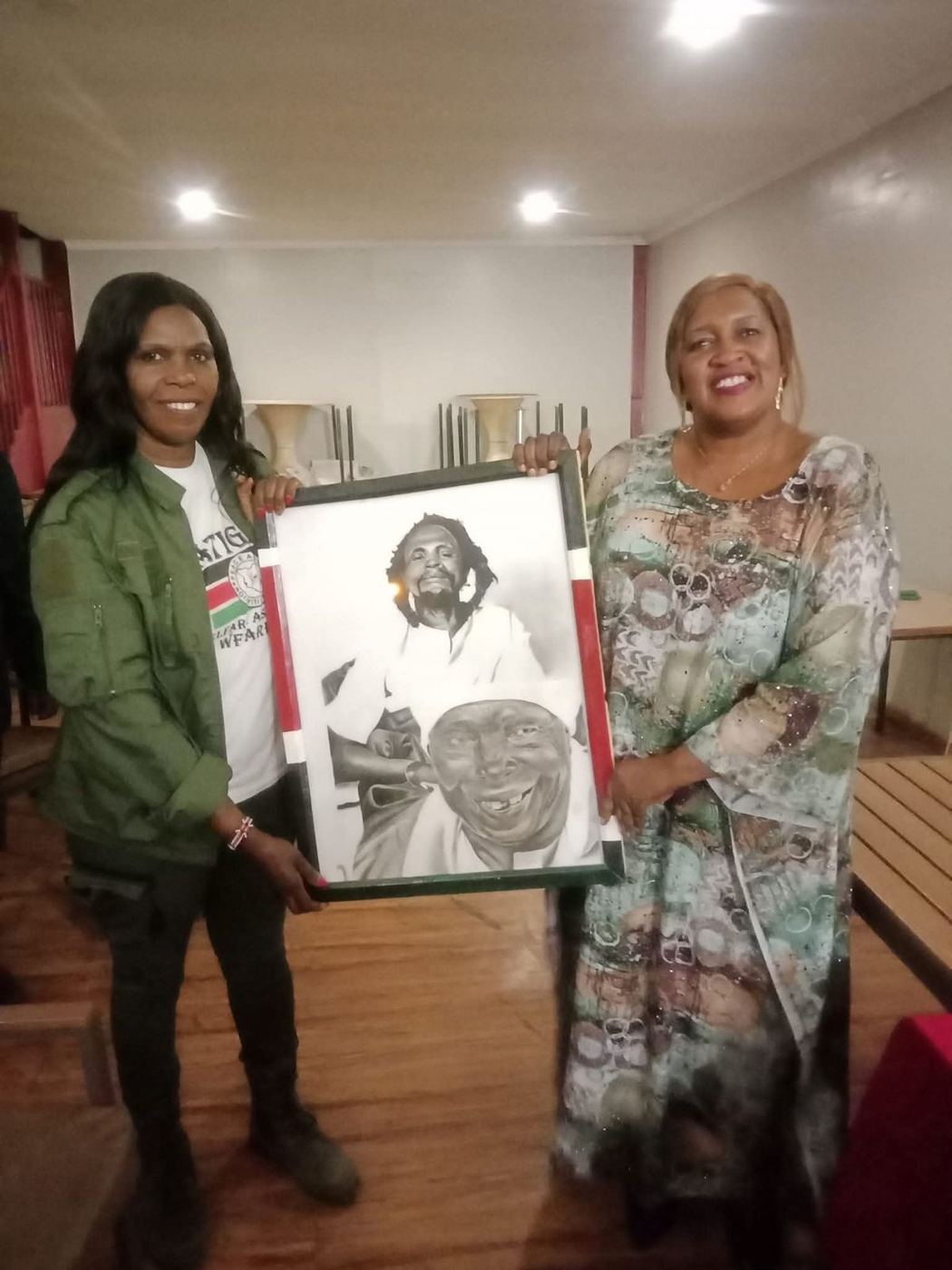 Hon. Anastasia Wanjiku N., Head of the Secretariat, with Wanjugu Kimathi, daughter of Field Marshal Dedan Kimathi, holding a framed portrait honouring the Kimathi legacy